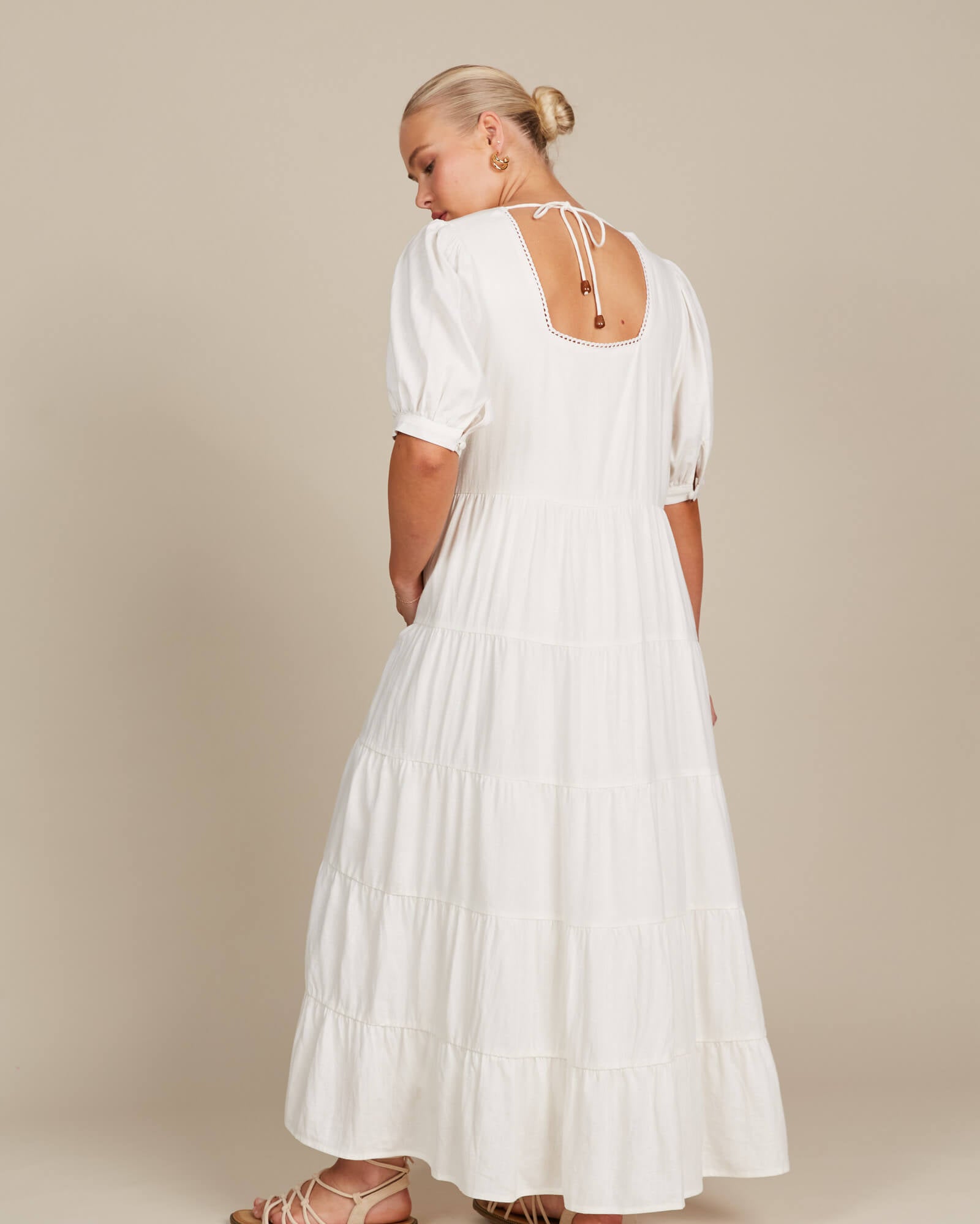 female model in a white dress showcasing the back of the dress