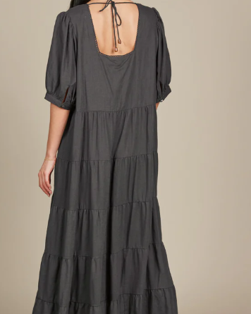 Dark hair model in a grey dress facing the wall