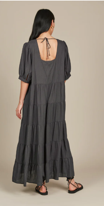 Dark hair model in a grey dress facing the wall