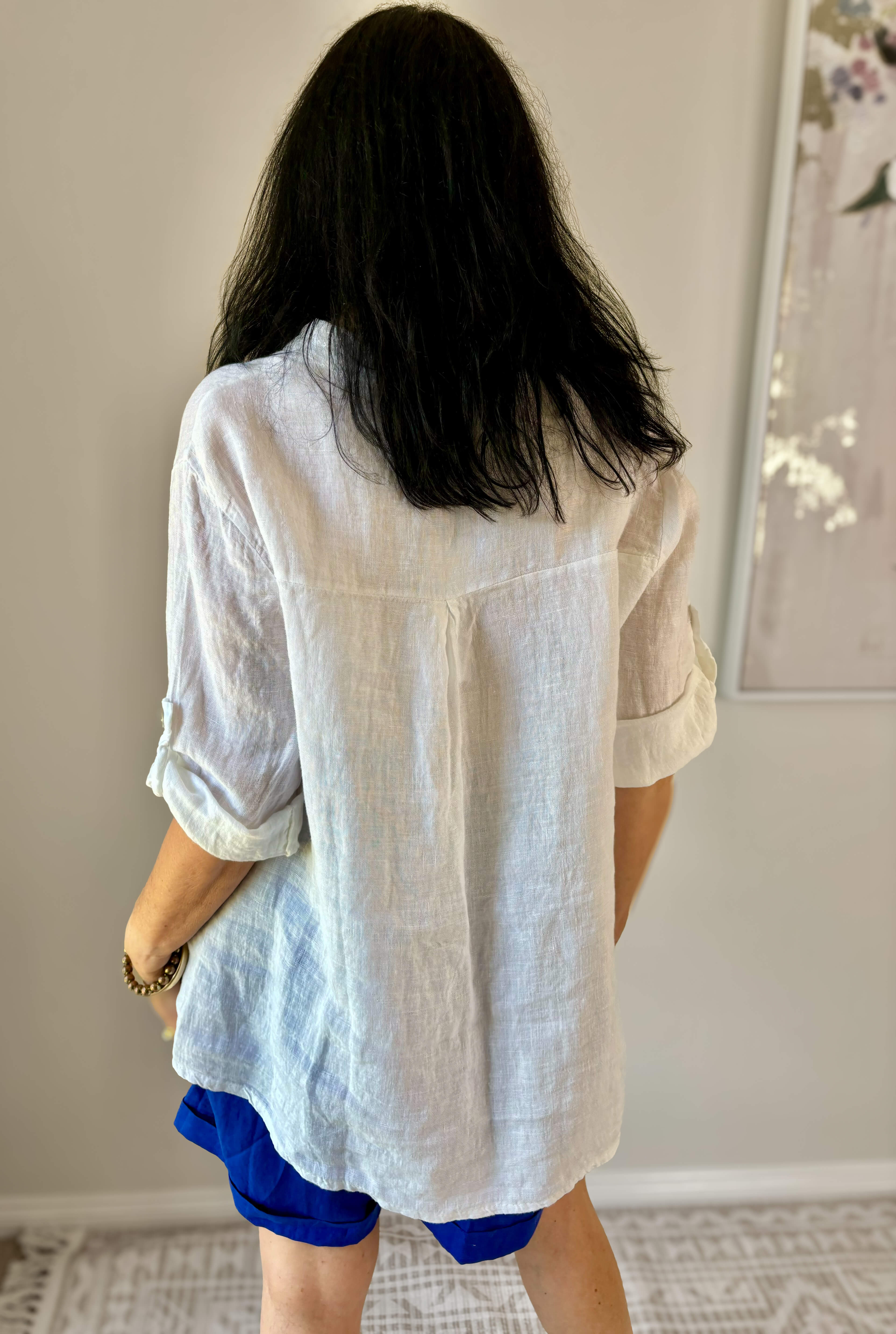 Lady standing with her back towards camera in white shirt