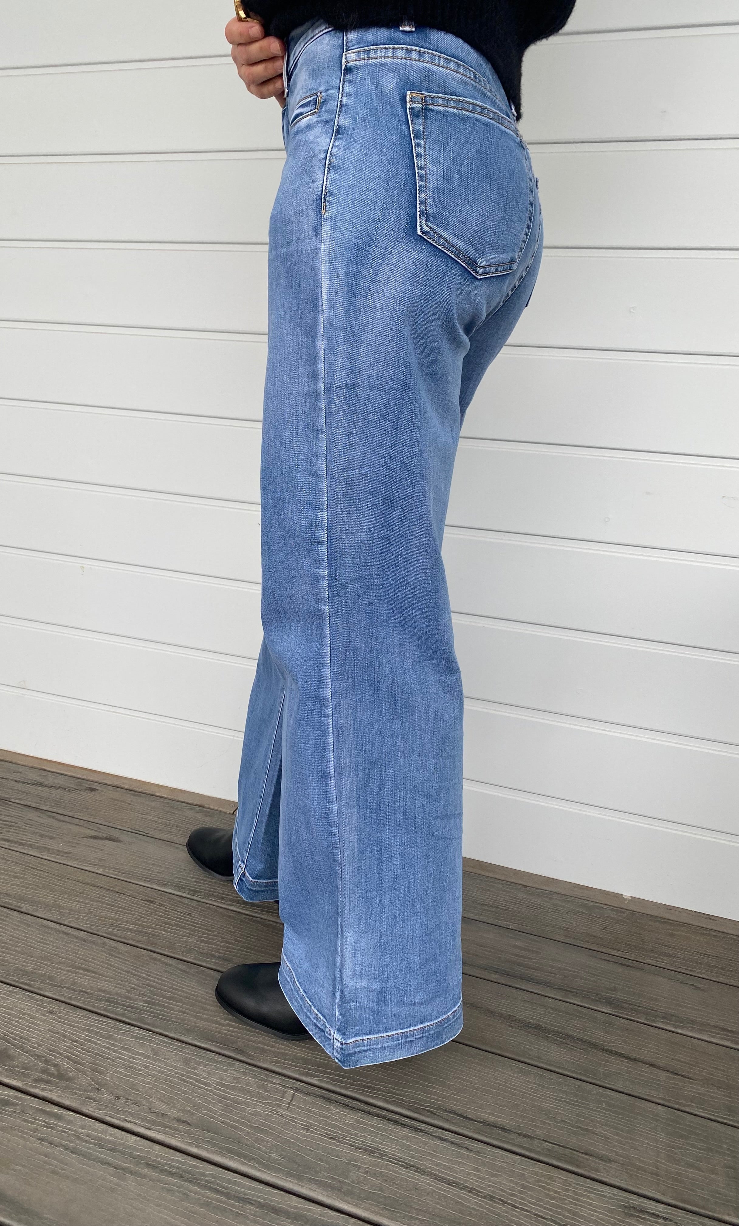 A stylish woman wearing a black sweater knit paired with wide-leg blue jeans, embodying a chic and casual look.