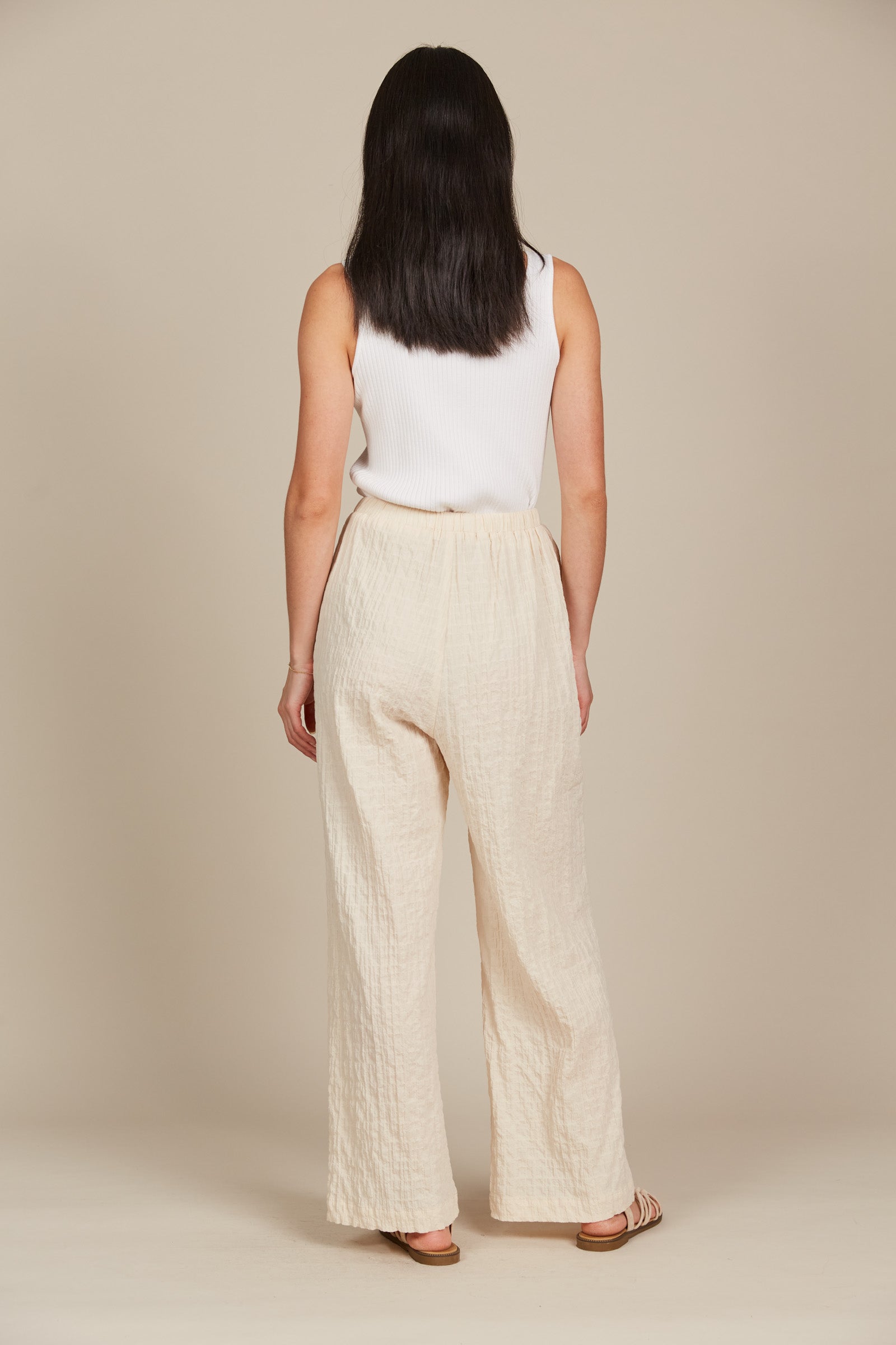 Model in cream cotton and spandex relaxed fit pants with drawstring and white tank