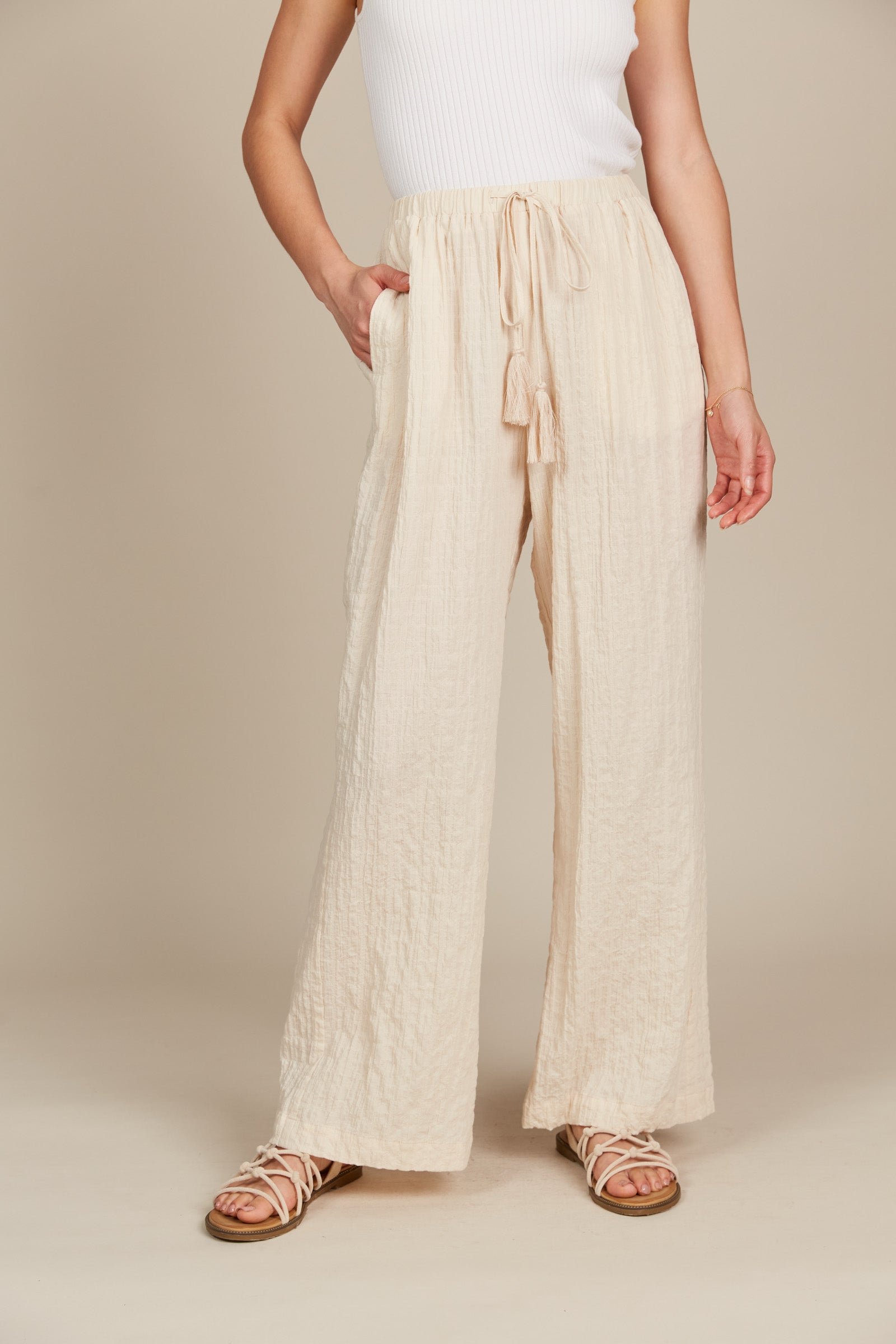 Model in cream cotton and spandex relaxed fit pants with drawstring and white tank
