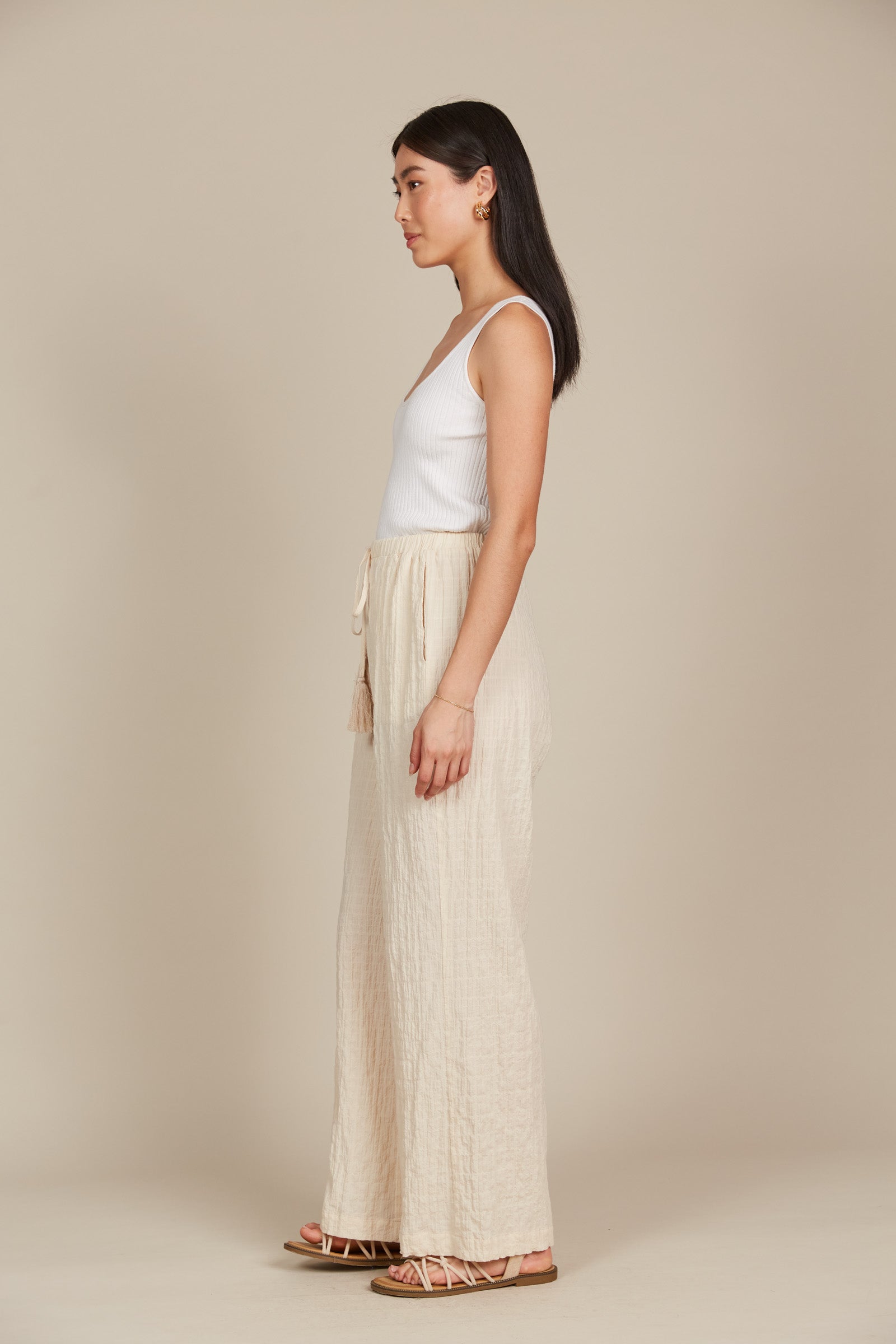 Model in cream cotton and spandex relaxed fit pants with drawstring and white tank