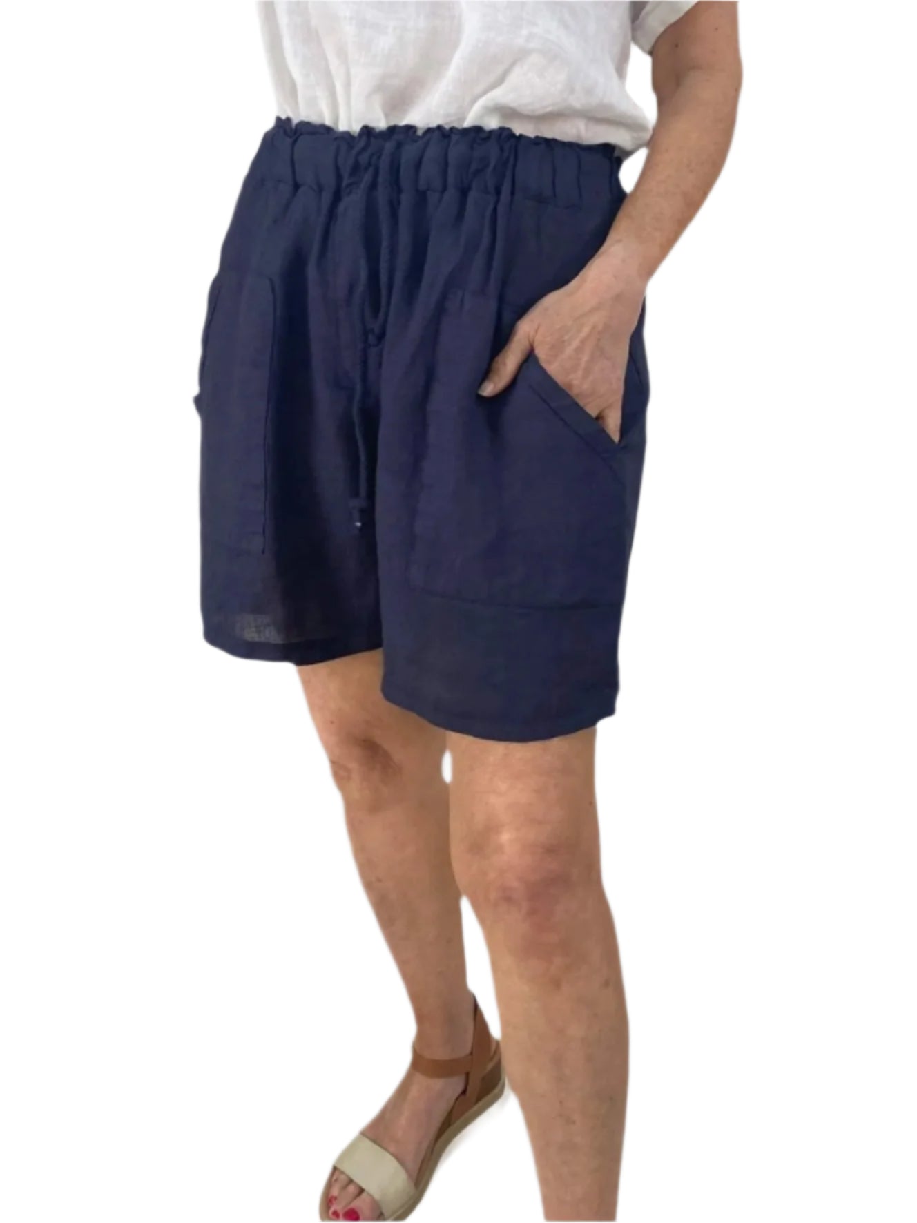 A woman dressed in a white shirt and blue shorts stands confidently, showcasing a casual summer outfit.