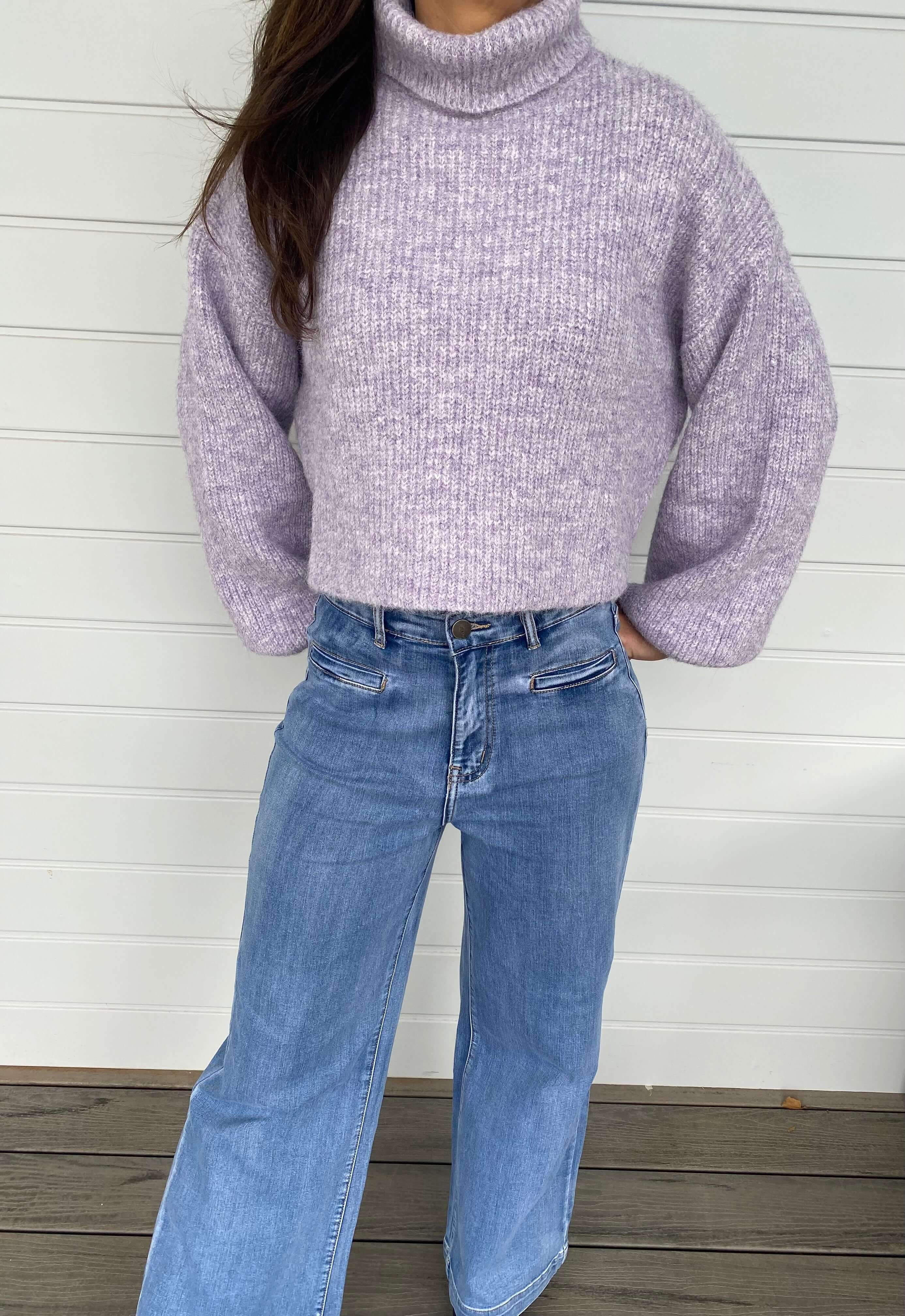 Women standing with a purple knit jumper and blue jeans