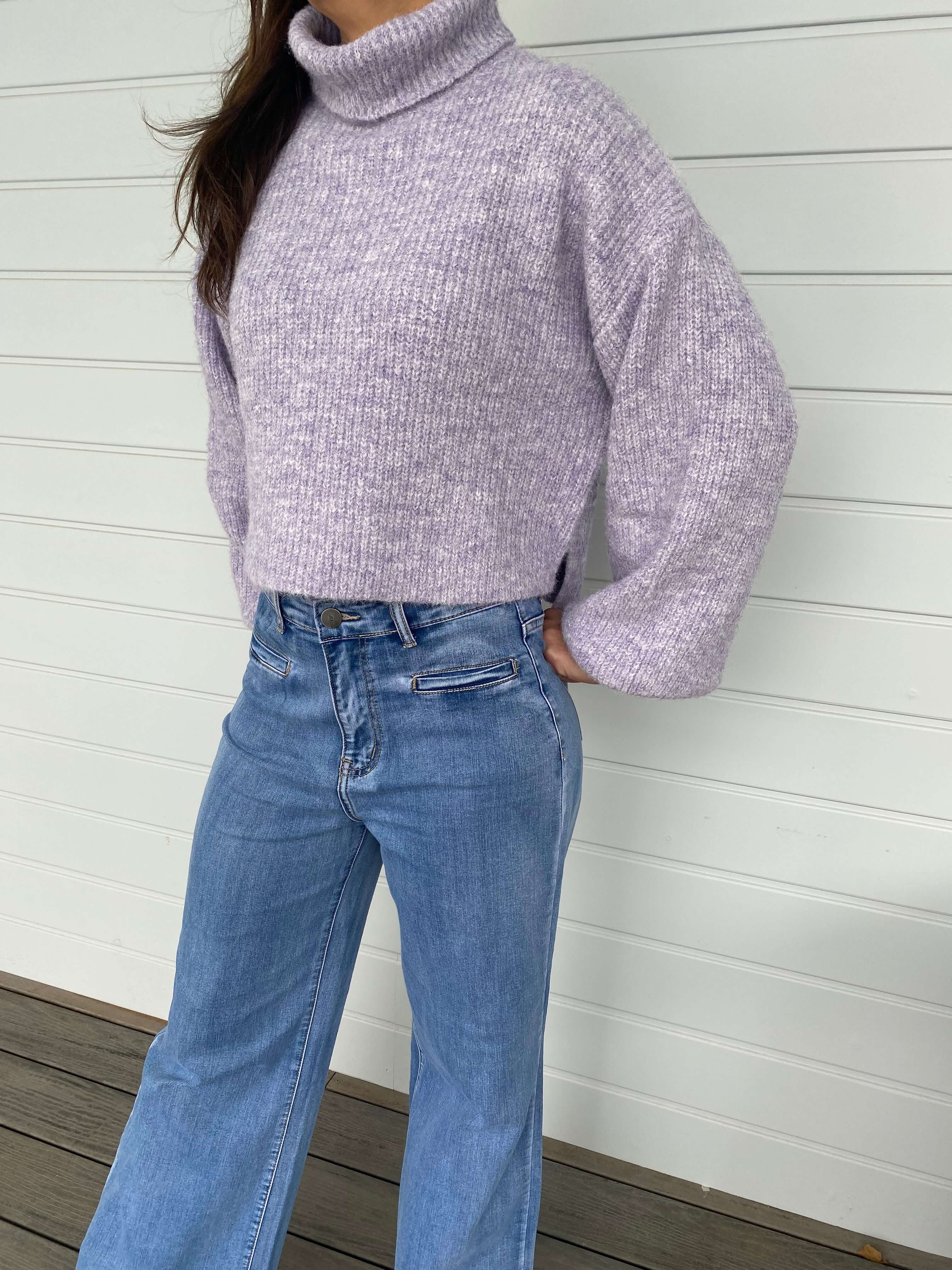 Women posing in a purple knit jumper and blue jeans