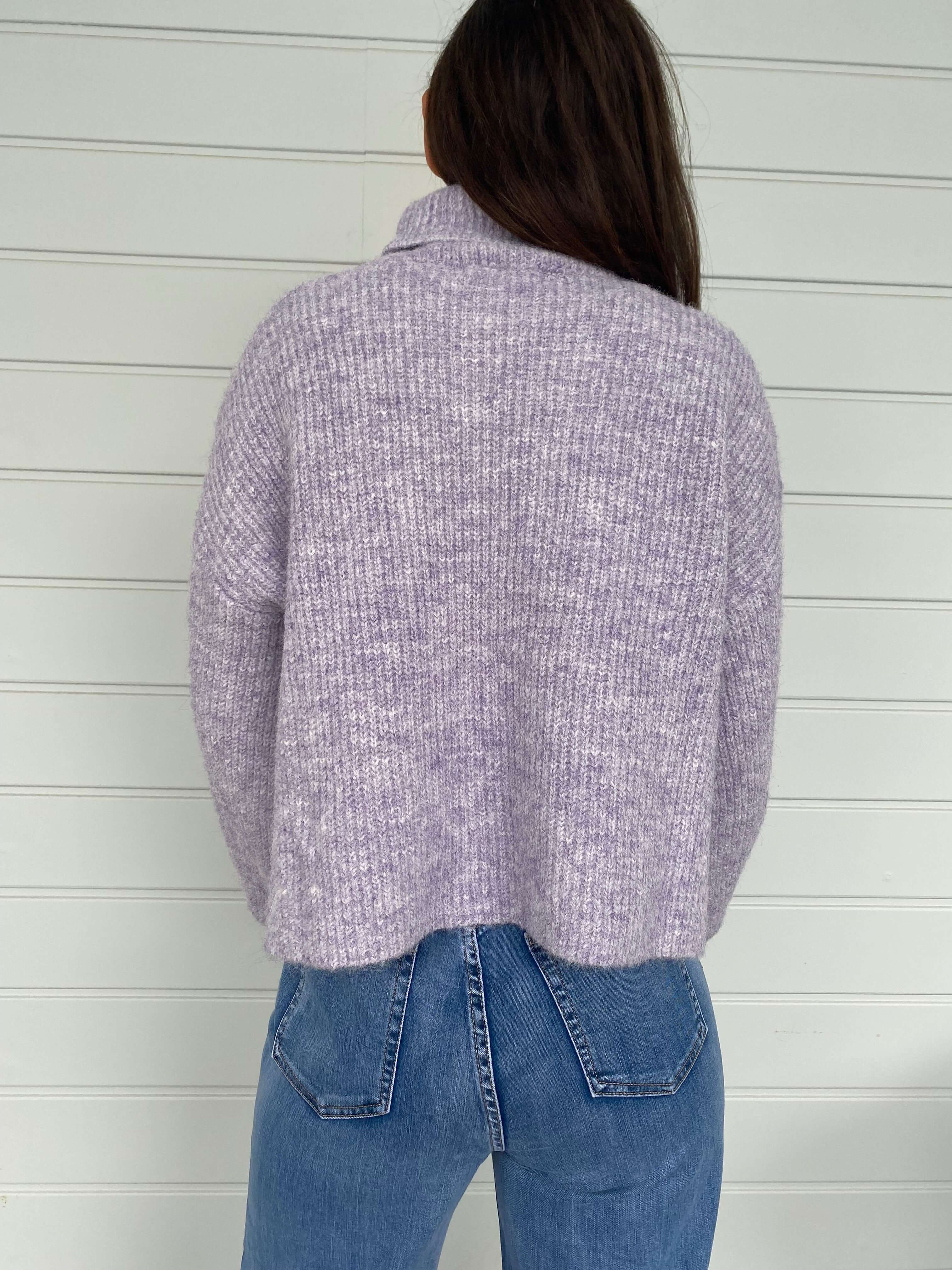 Women posing in a purple knit jumper and blue jeans