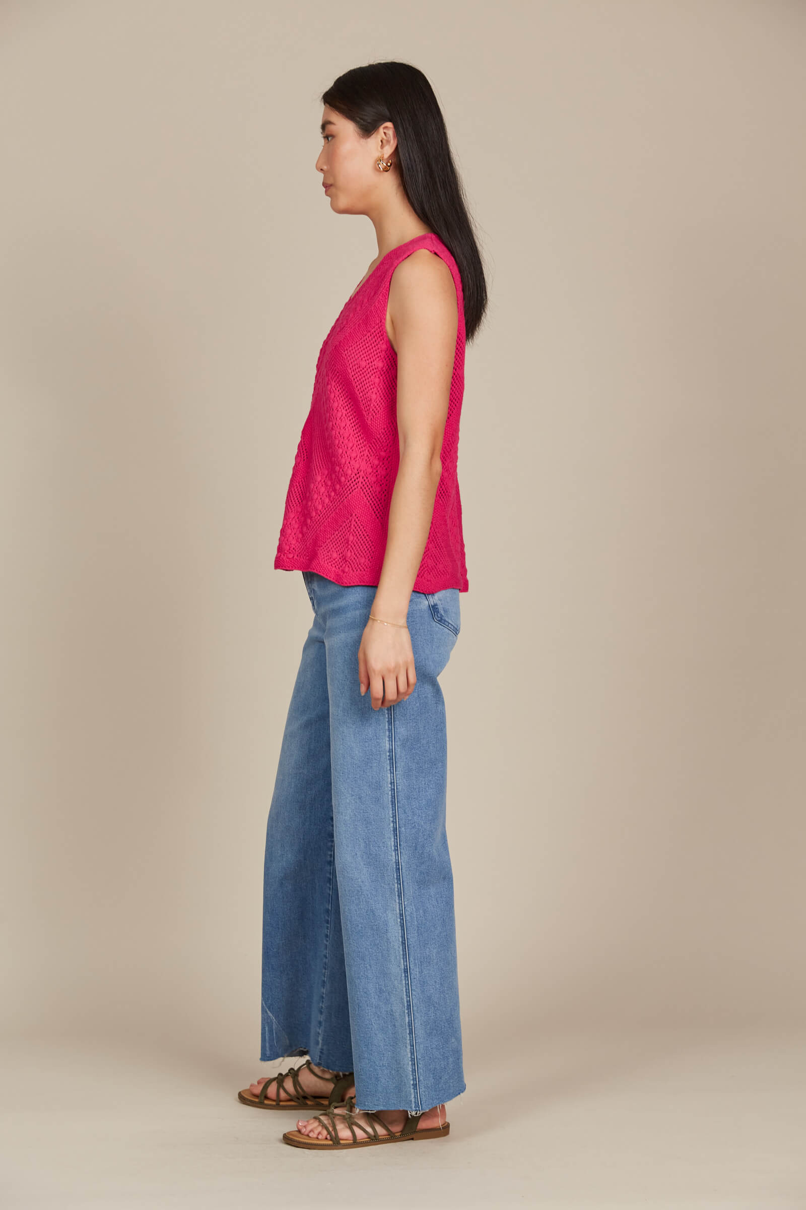 A woman seen from the side, wearing a pink top and jeans, standing confidently in a casual setting.