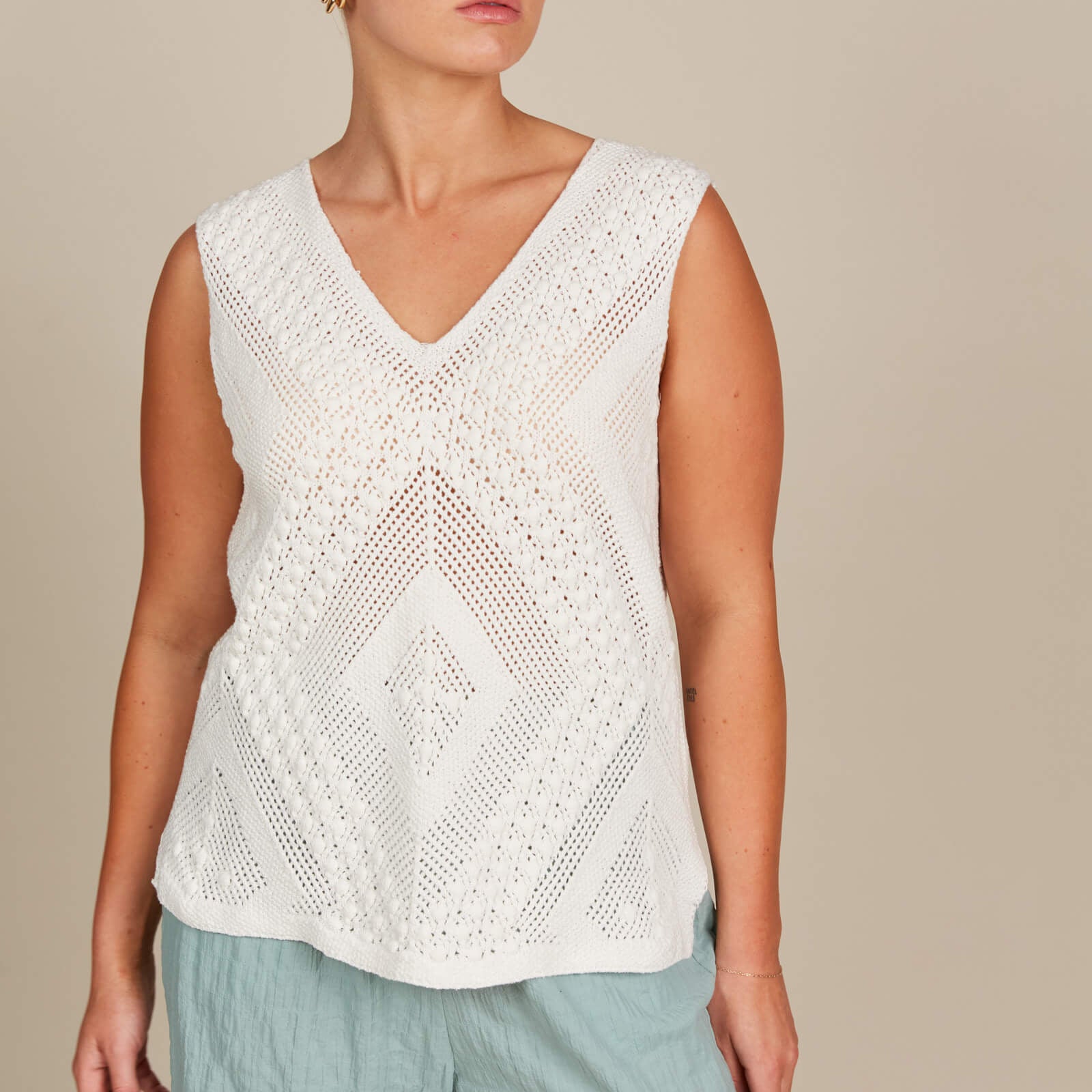 A woman wearing a white top and blue pants, standing confidently in a casual setting.