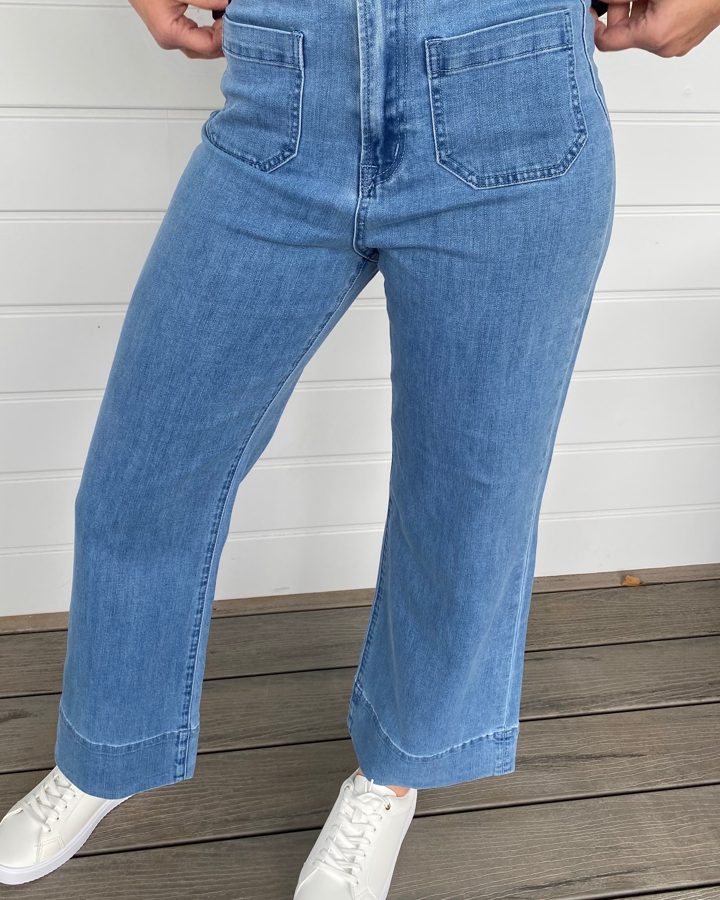 Women standing in blue denim jeans and black blouse with white sneakers