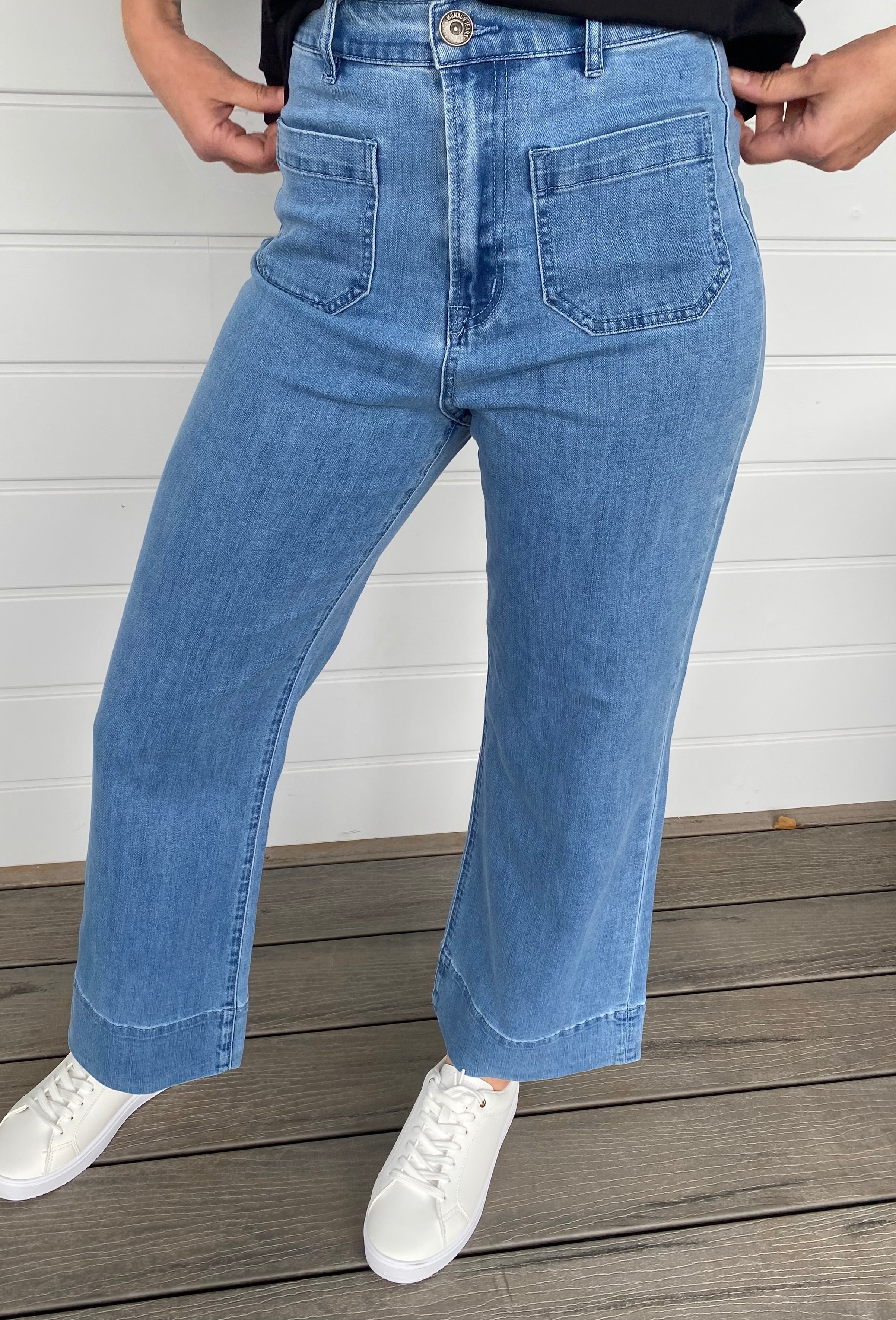 Women standing in blue denim jeans and black blouse with white sneakers