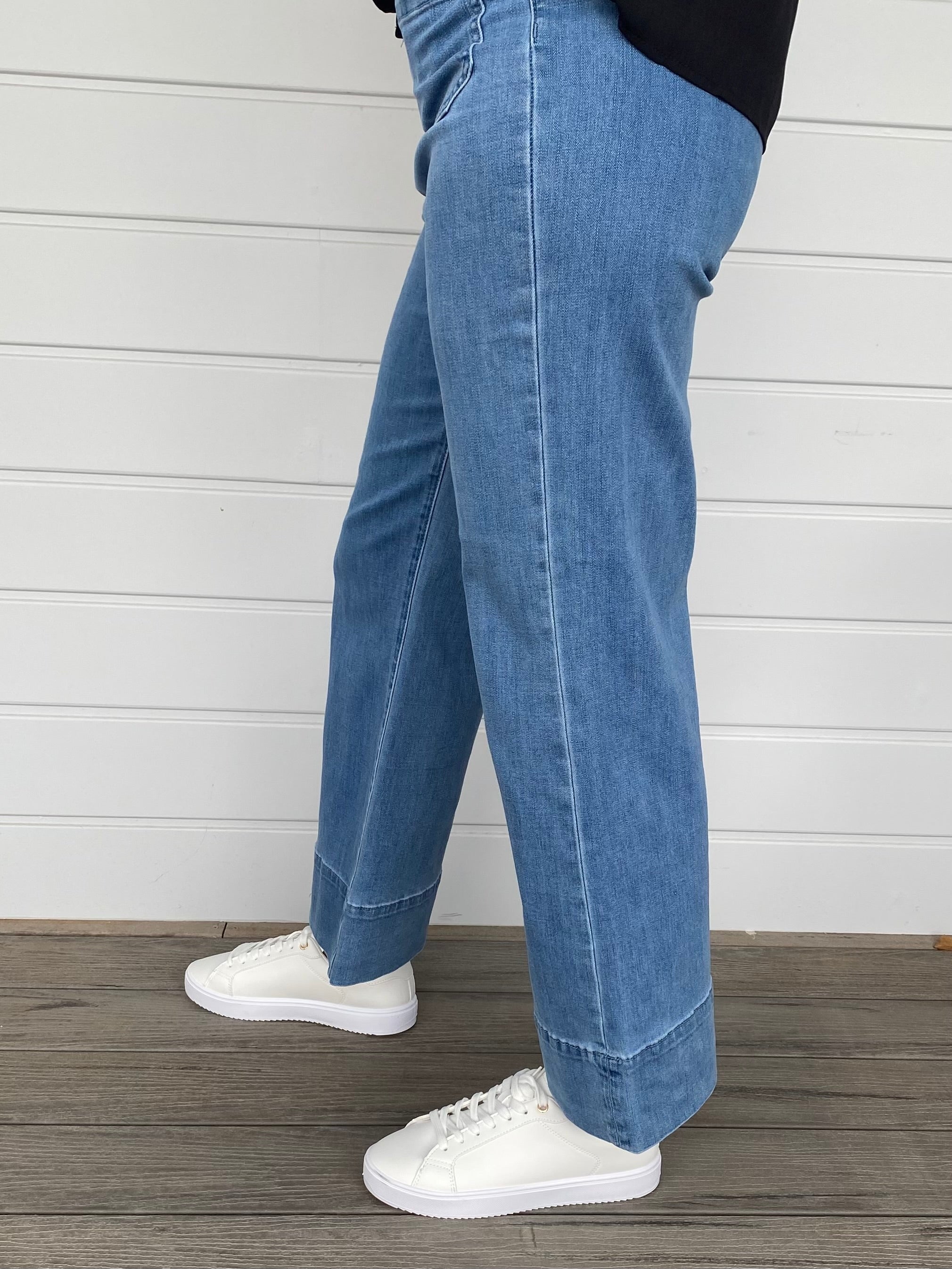 Women standing in blue denim jeans and black blouse with white sneakers