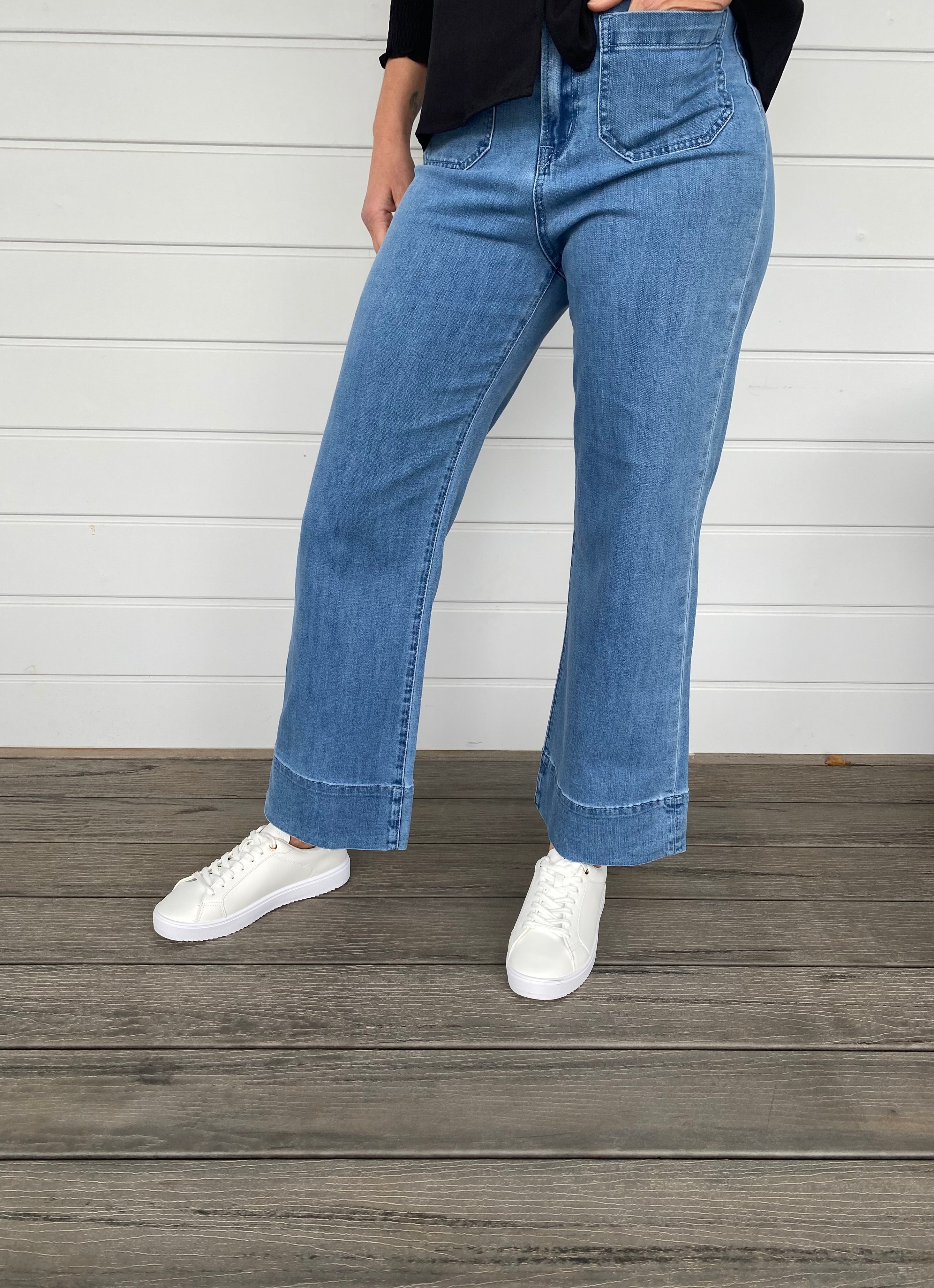 Women standing in blue denim jeans and black blouse with white sneakers