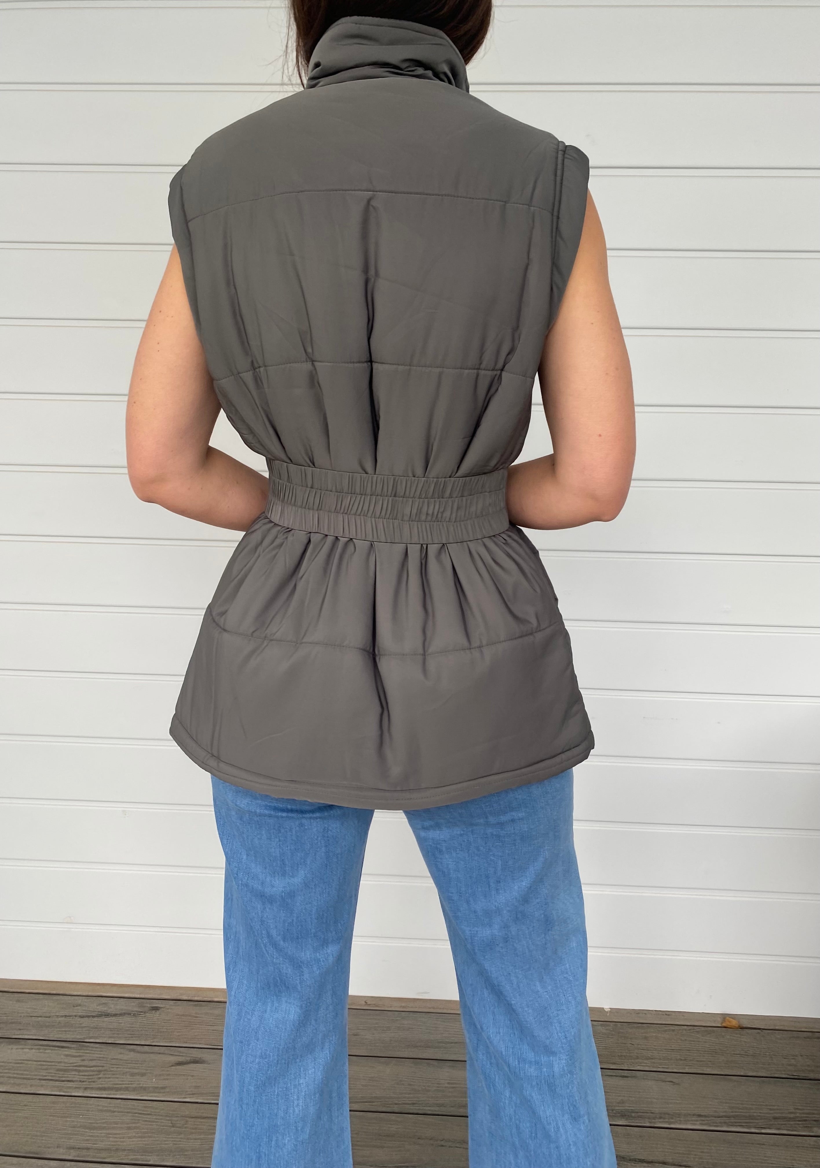 Woman standing in a grey puffer jacket with blue jeans