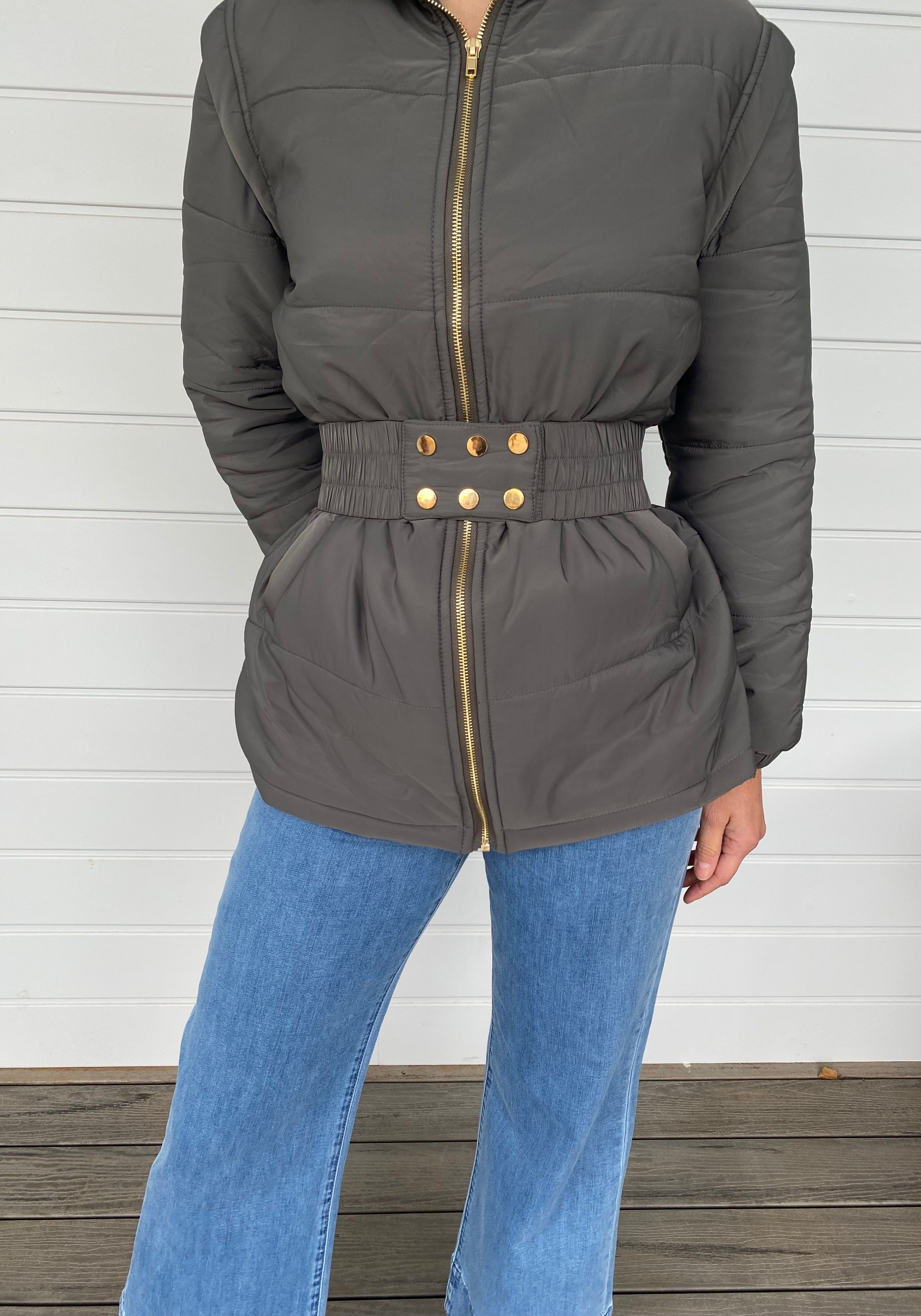 Woman standing in a grey puffer jacket with blue jeans
