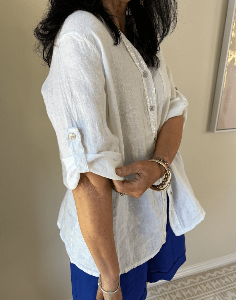 Lady in a white shirt holding her rolled up sleeve