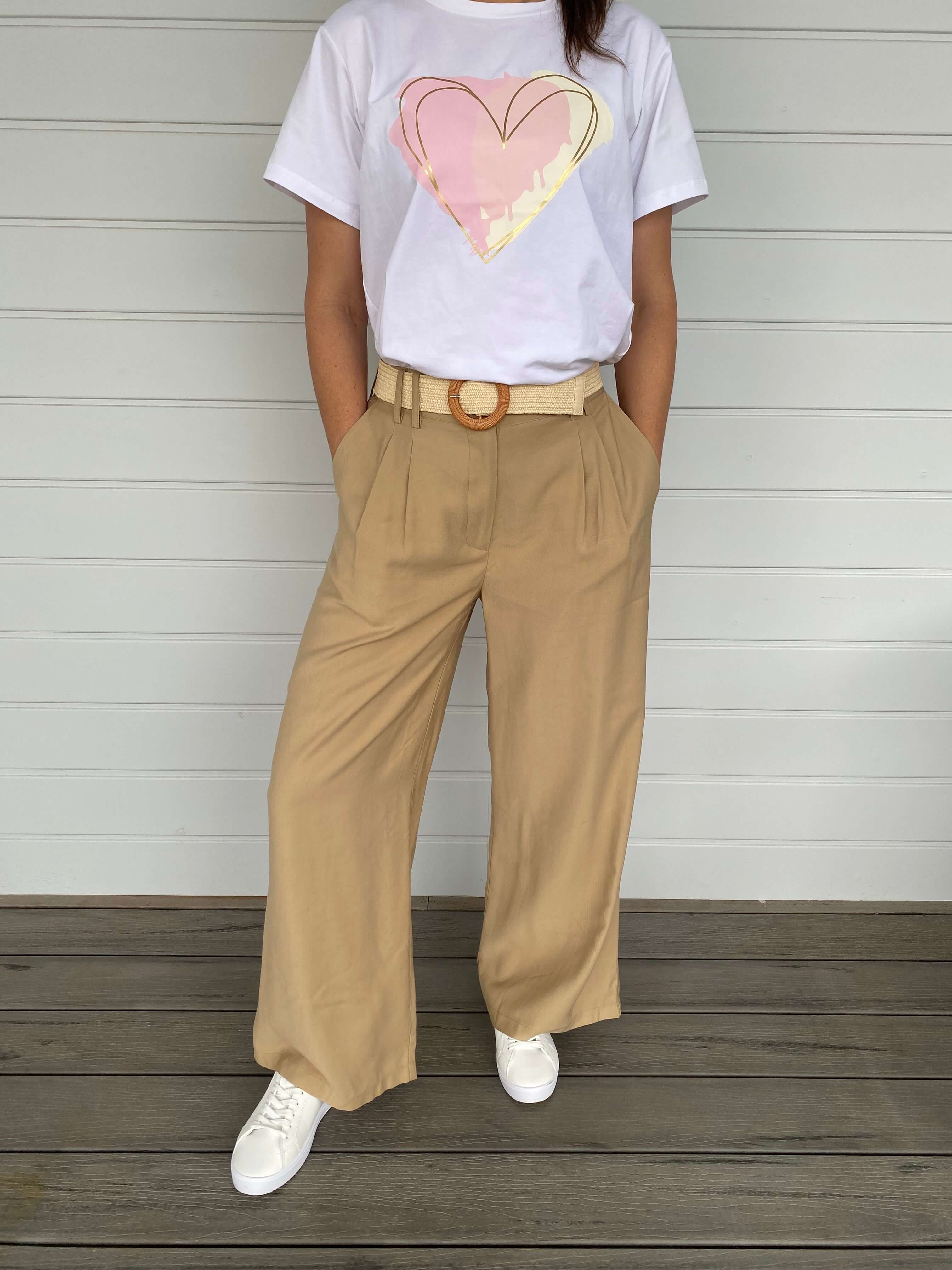 Women in beige pants with wide leg, cream belt and white t shirt