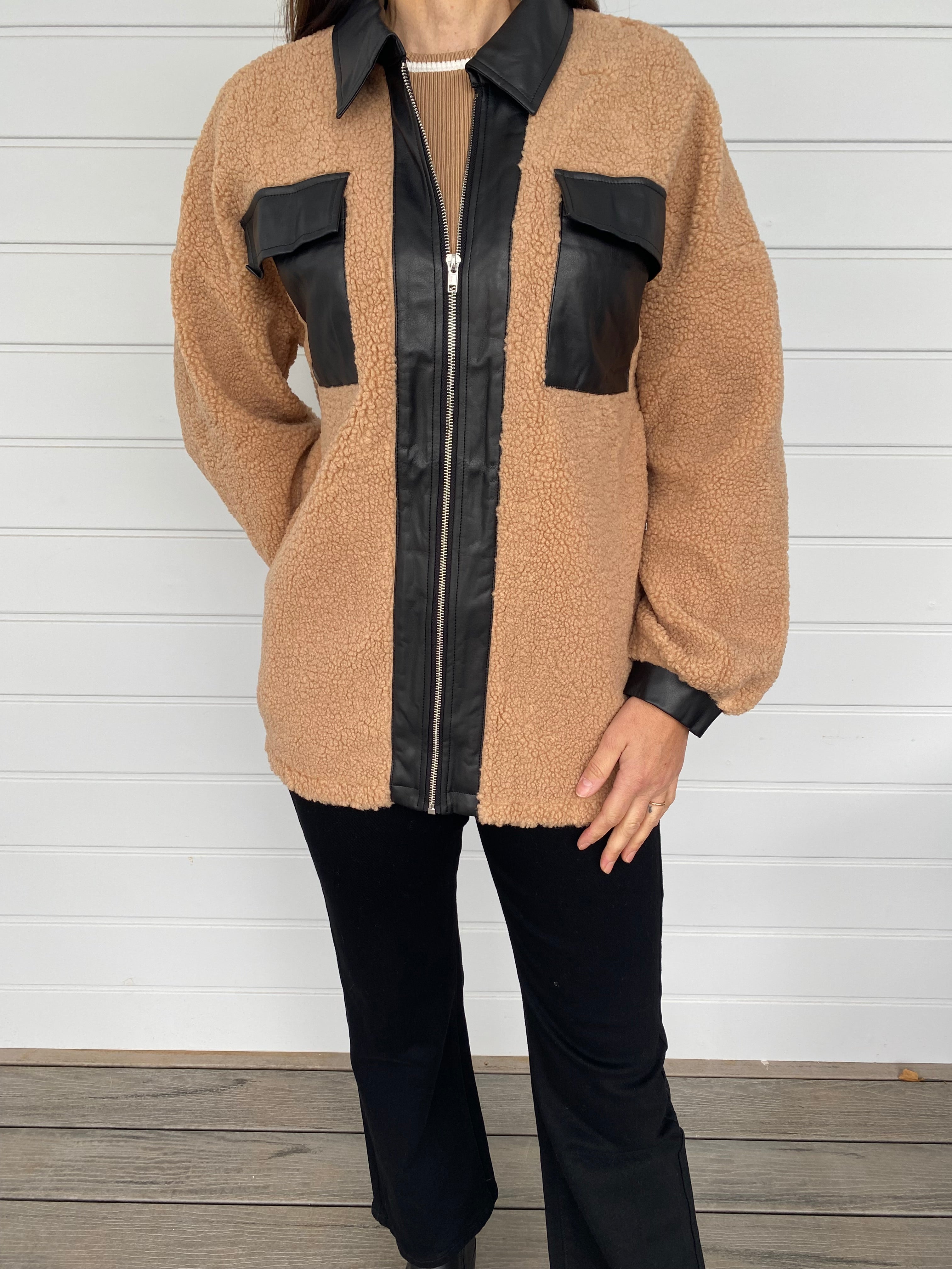 Woman modeling tan and black accent jacket with black jeans