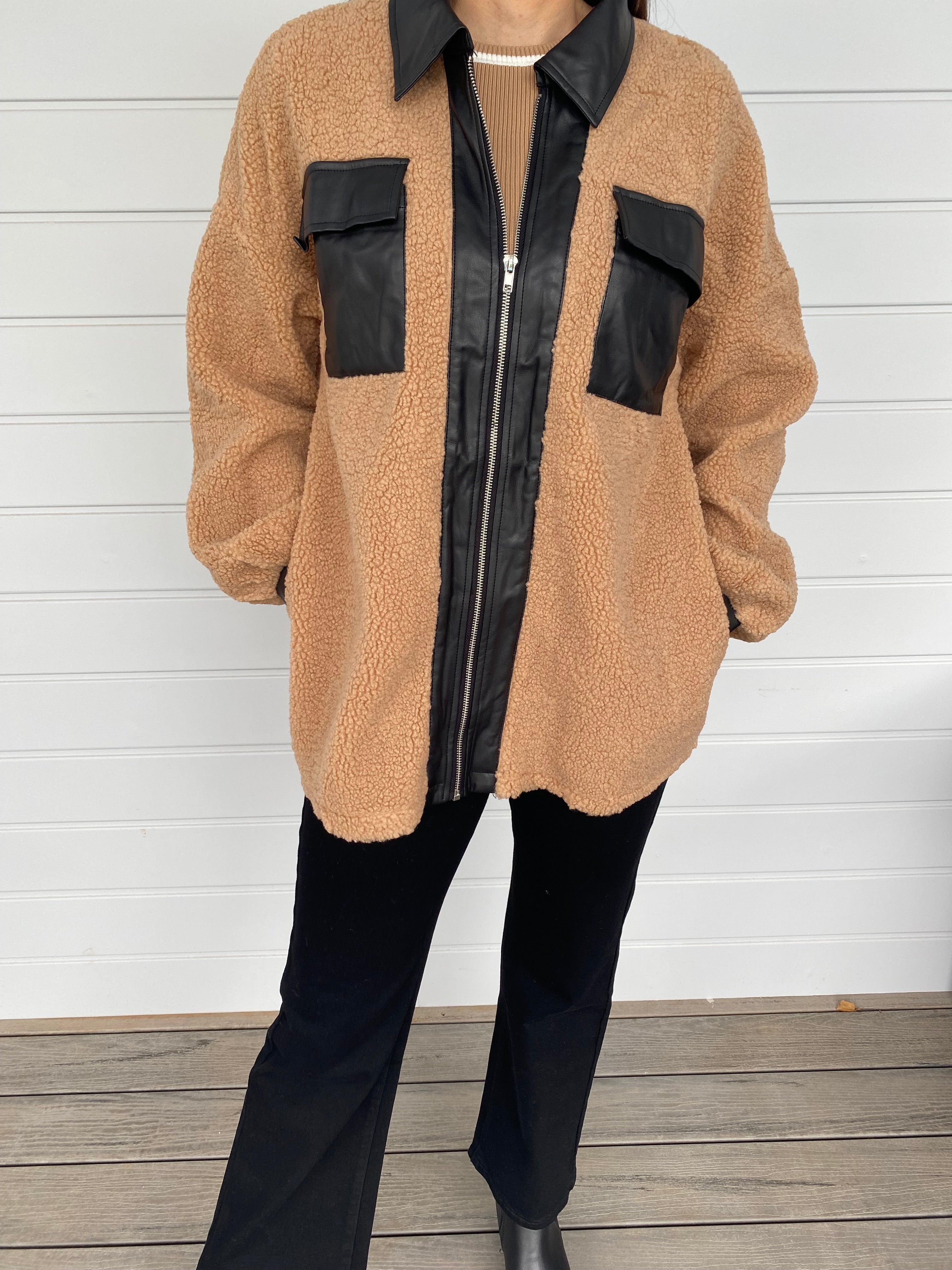 Woman modeling tan and black accent jacket with black jeans