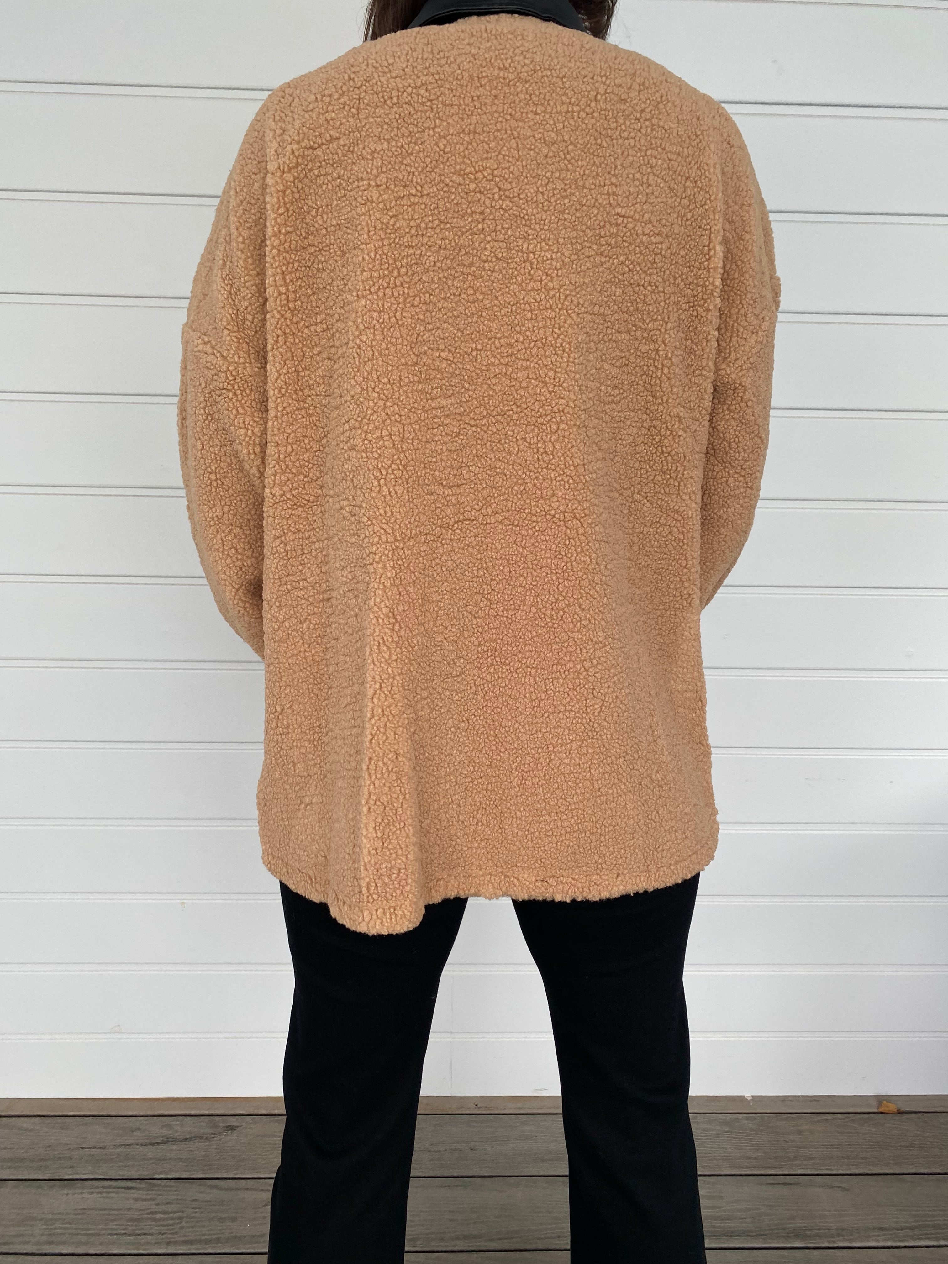 Woman modeling tan and black accent jacket with black jeans