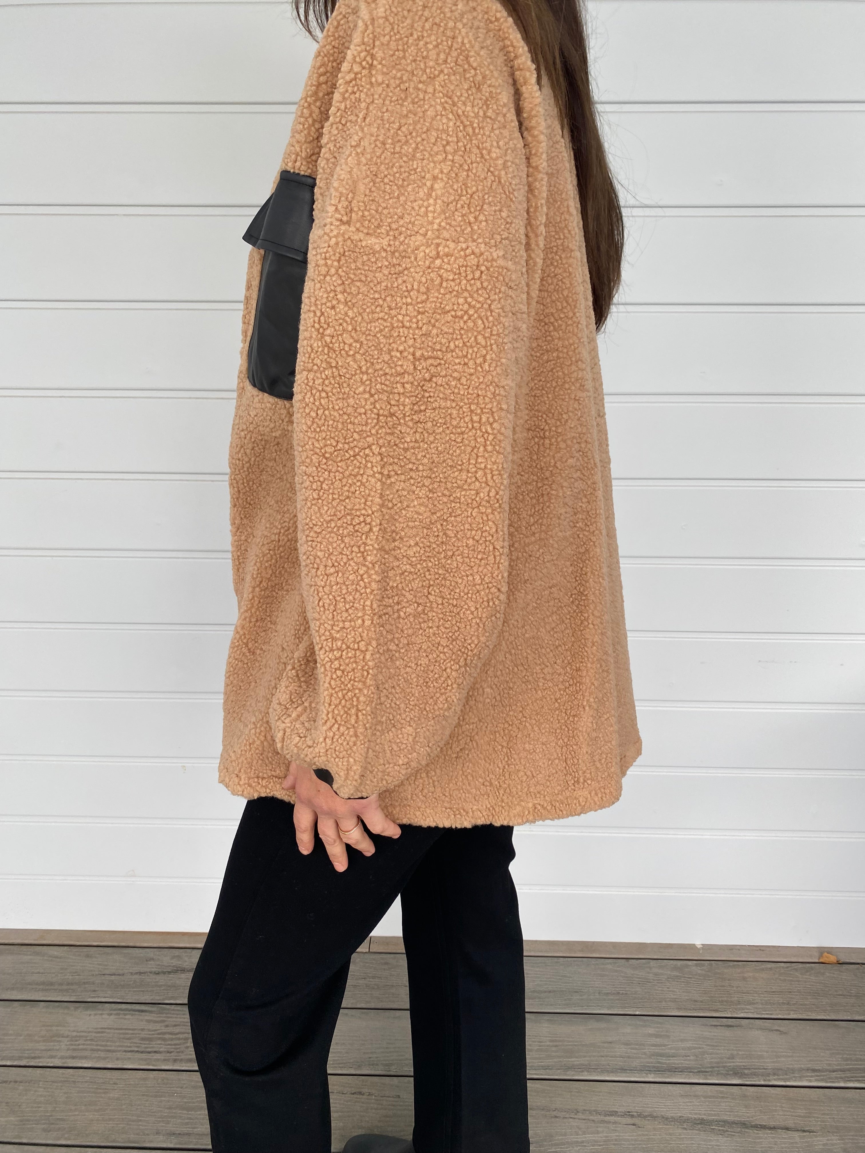 Woman modeling tan and black accent jacket with black jeans