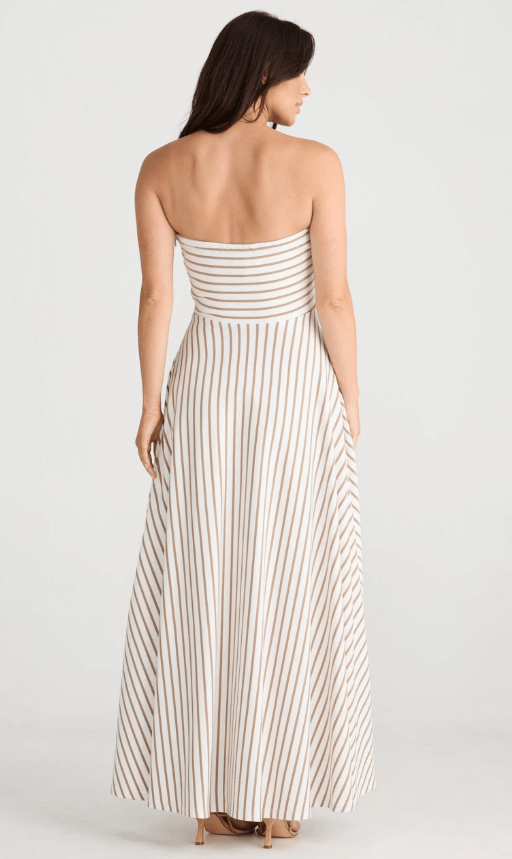 Model posing in a brown striped white strapless dress