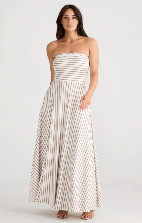 Model posing in a brown striped white strapless dress