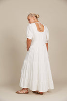 female model in a white dress showcasing the back of the dress