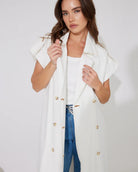 Woman in white denim longline vest and blue jeans