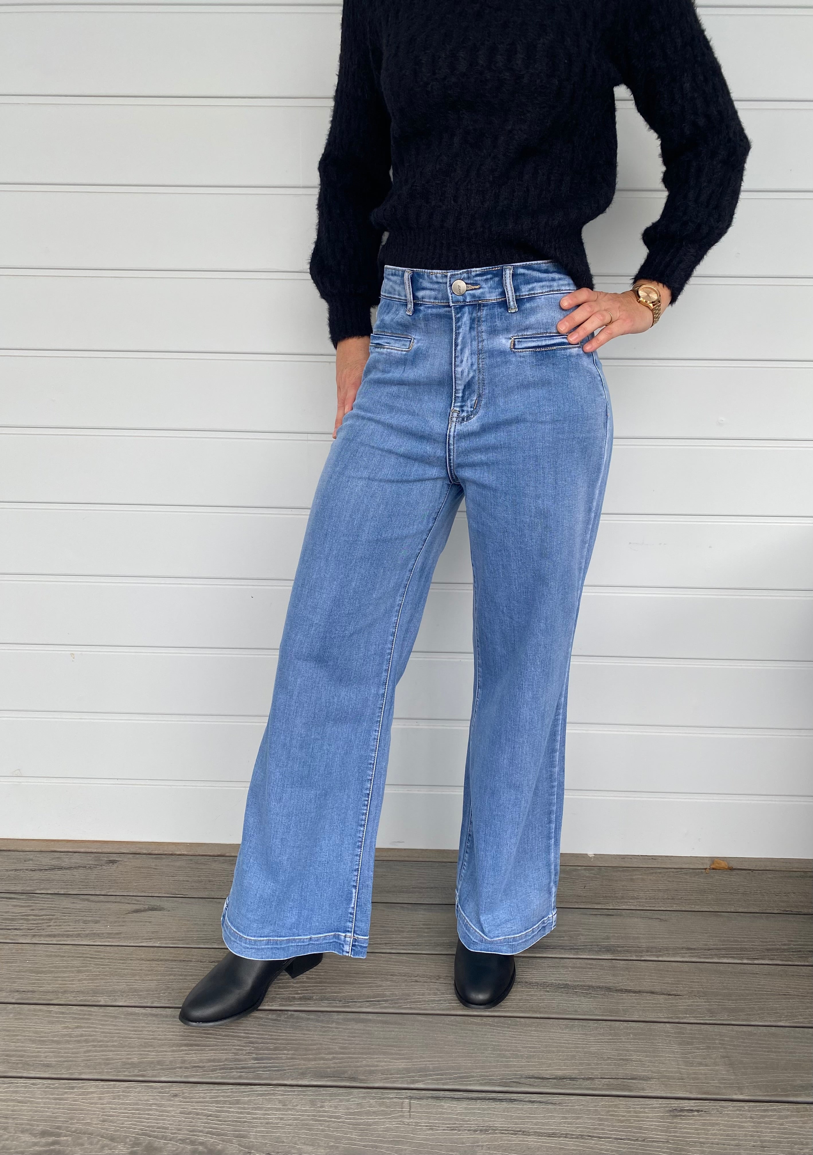  A stylish woman wearing a black sweater knit paired with wide-leg blue jeans, embodying a chic and casual look.