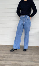  A stylish woman wearing a black sweater knit paired with wide-leg blue jeans, embodying a chic and casual look.