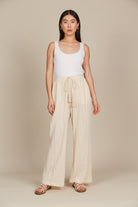 Model in cream cotton and spandex relaxed fit pants with drawstring and white tank