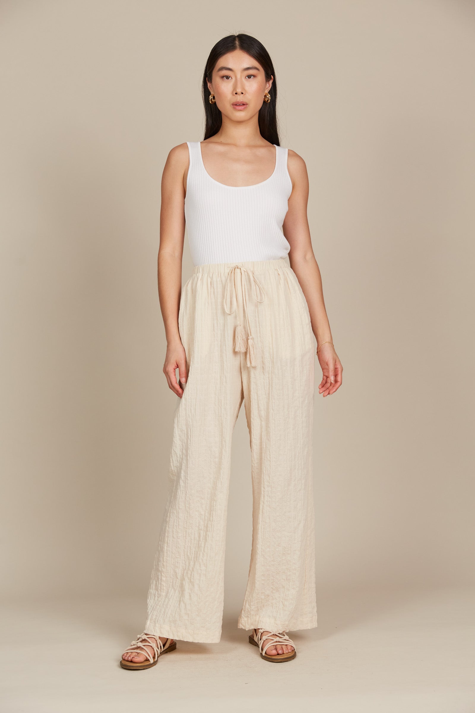 Model in cream cotton and spandex relaxed fit pants with drawstring and white tank