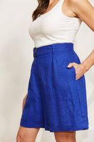Model side on in blue shorts and white top