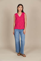 A woman seen from the front, wearing a pink top and jeans, standing confidently in a casual setting.