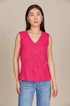 Close up of a woman wearing a pink top and jeans, standing confidently in a casual setting.