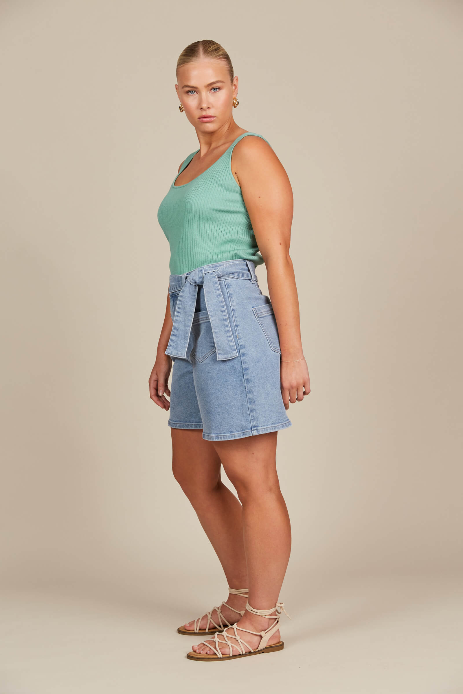 Model posing in denim shorts and green tank