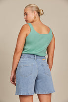 Model in denim shorts and green tank