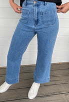 Women standing in blue denim jeans and black blouse with white sneakers