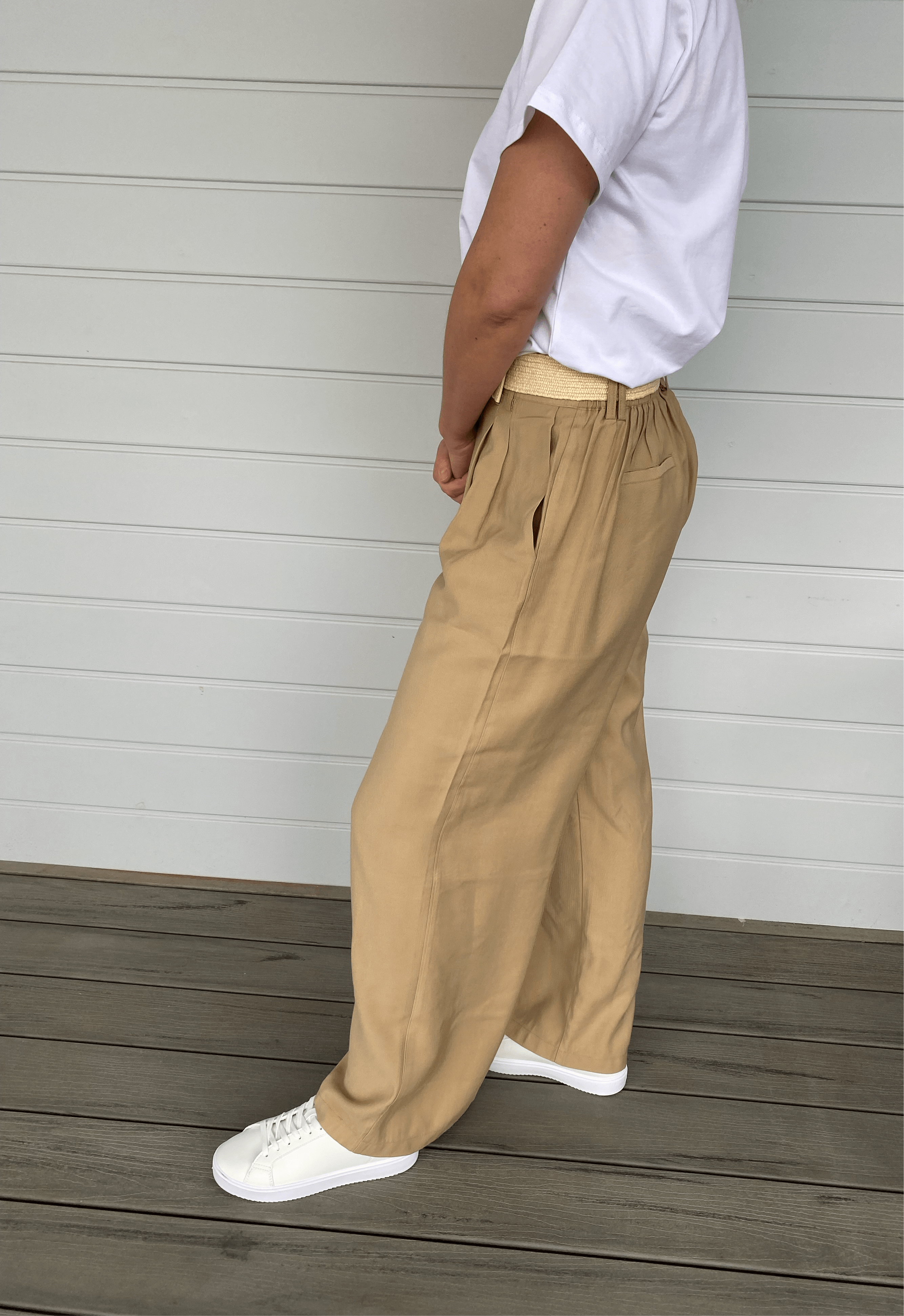 Women in beige pants with wide leg, cream belt and white t shirt