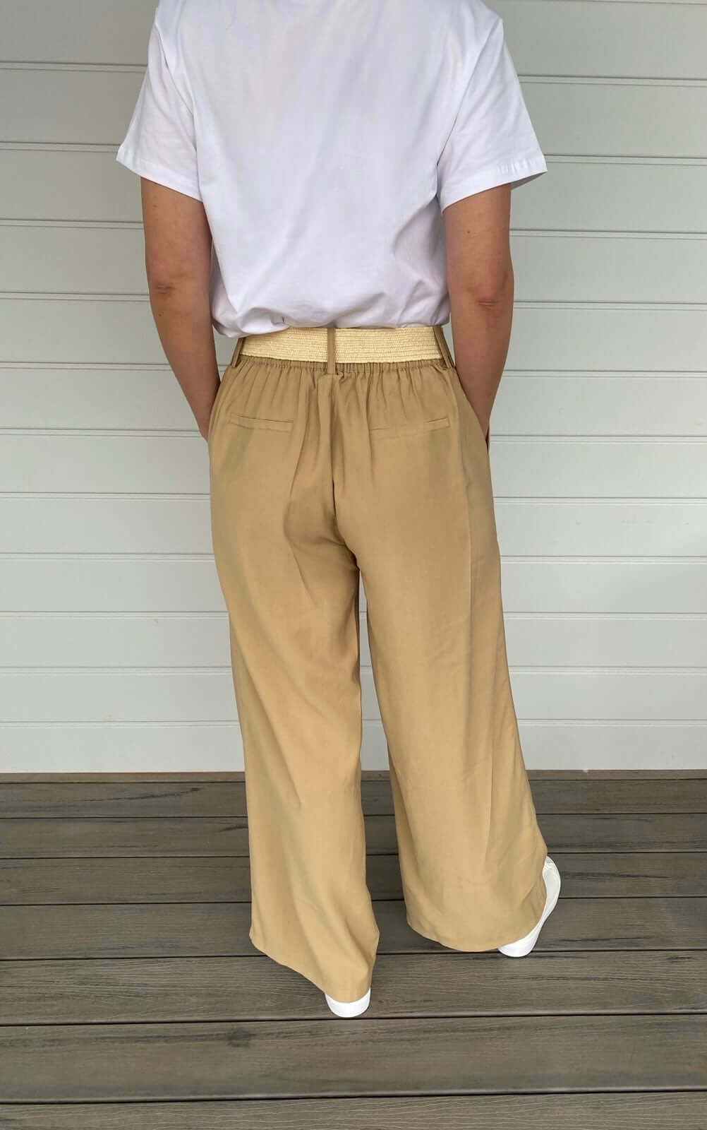 Women in beige pants with wide leg, cream belt and white t shirt
