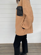 Woman modeling tan and black accent jacket with black jeans