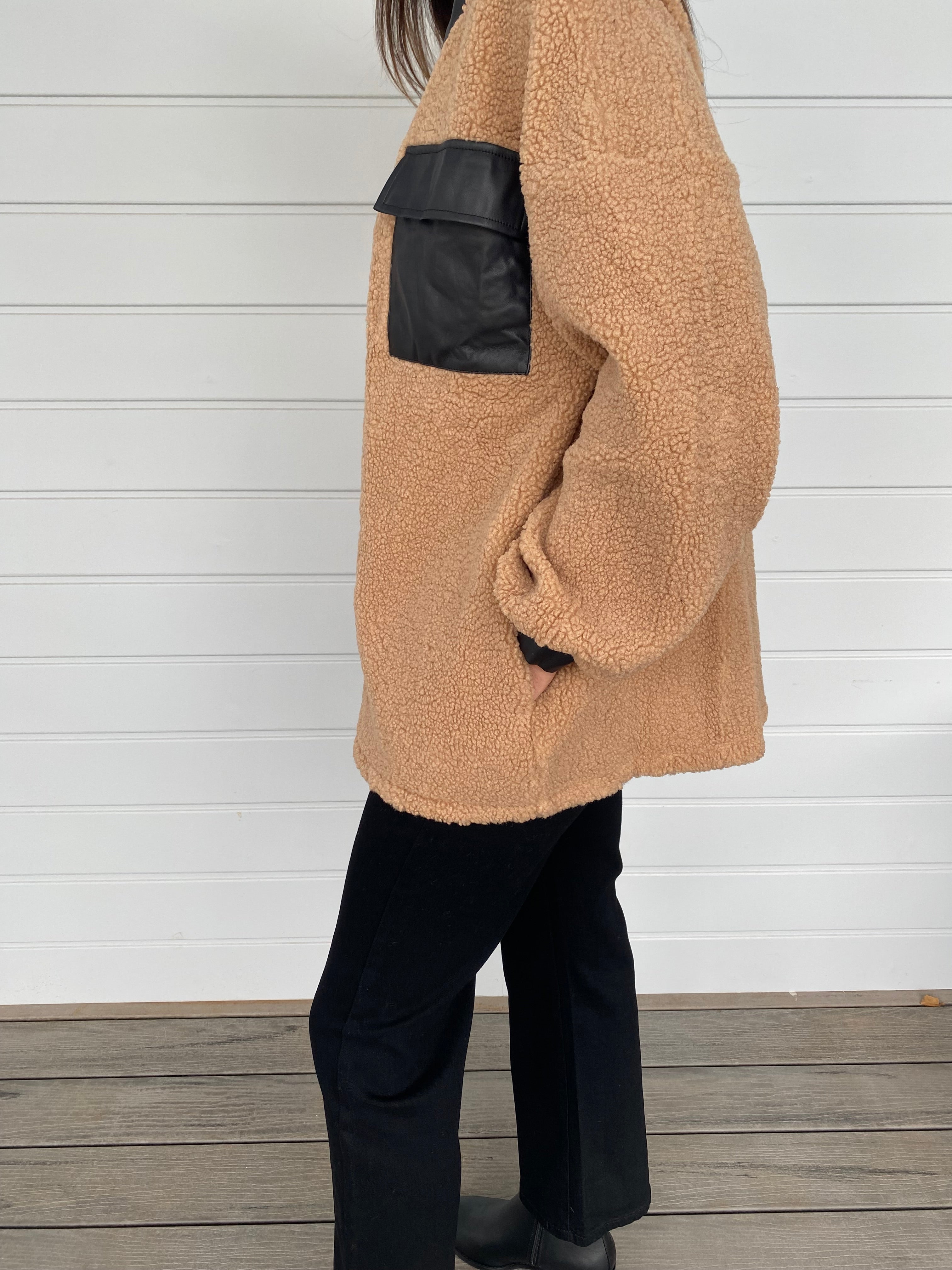 Woman modeling tan and black accent jacket with black jeans